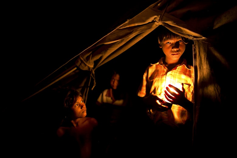 Child Holds Candle Outside His Tent